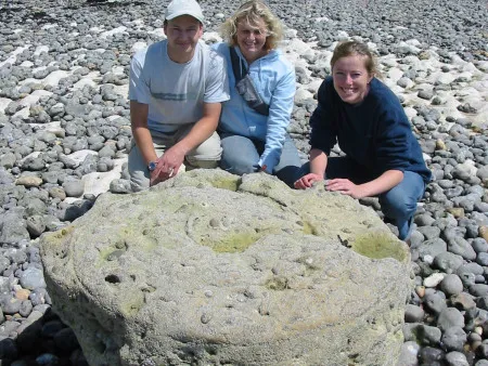 Robert Randell, Denise Randell and Lucinda Shepherd crouched behind a giant Parapuzosia ammonite at Peacehaven